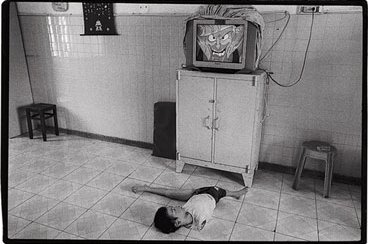 Un niño que nació sin brazos ve la televisión en Saigón. Foto: James Nachtwey